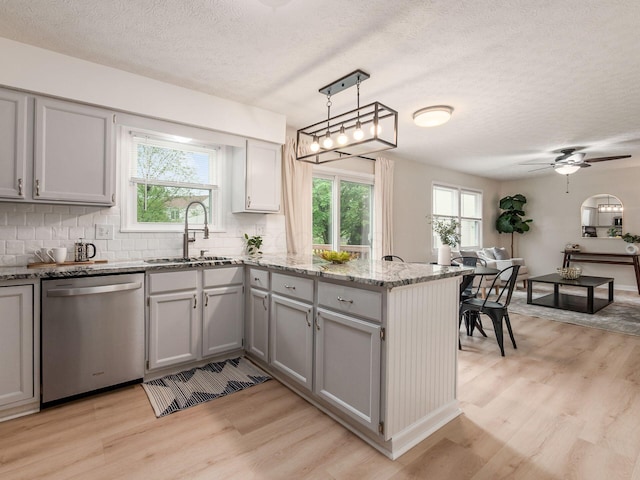 1520 Dickson Dr, Columbus, OH 43228 - kitchen featuring stainless steel dishwasher, a sink, a peninsula, light wood-style floors, and decorative backsplash