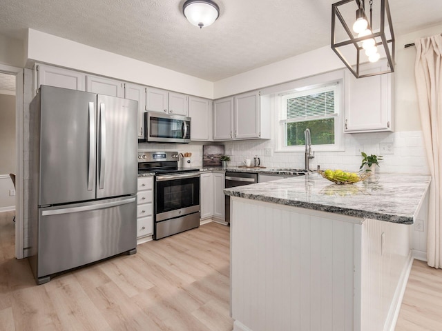 1520 Dickson Dr, Columbus, OH 43228 - kitchen with stainless steel appliances, a sink, light wood finished floors, a peninsula, and light stone countertops