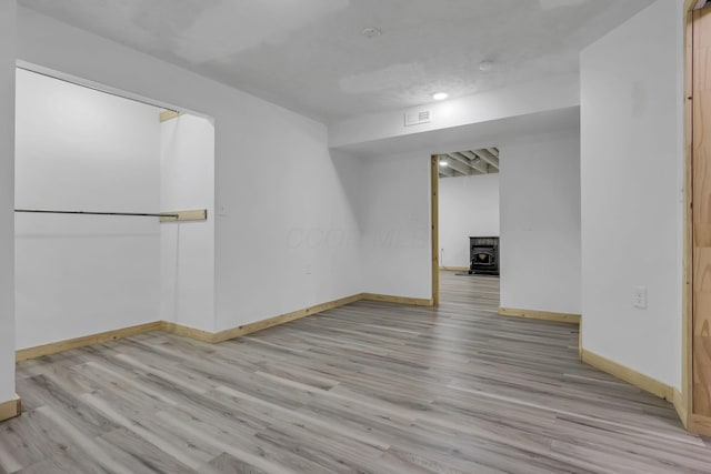 7205 W Grubb Rd NE, Thornville, OH 43076 - unfurnished room with a wood stove, baseboards, and light wood finished floors