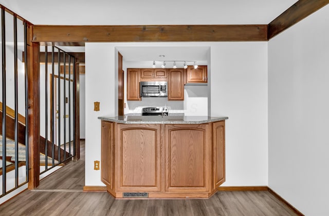 144 W Ticonderoga Dr Unit H, Westerville, OH 43081 - kitchen featuring appliances with stainless steel finishes, wood finished floors, baseboards, rail lighting, and brown cabinetry