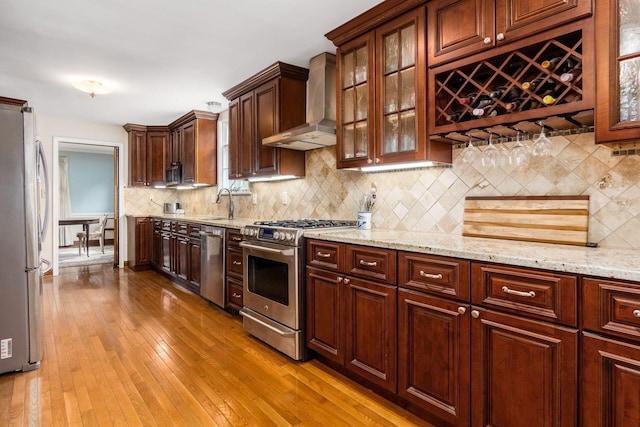 2731 E Broad St, Bexley, OH 43209 - kitchen featuring appliances with stainless steel finishes, wall chimney exhaust hood, wood-type flooring, and light stone counters