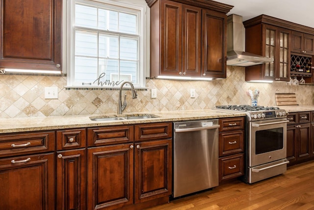2731 E Broad St, Bexley, OH 43209 - kitchen with stainless steel appliances, wall chimney range hood, a sink, wood finished floors, and tasteful backsplash