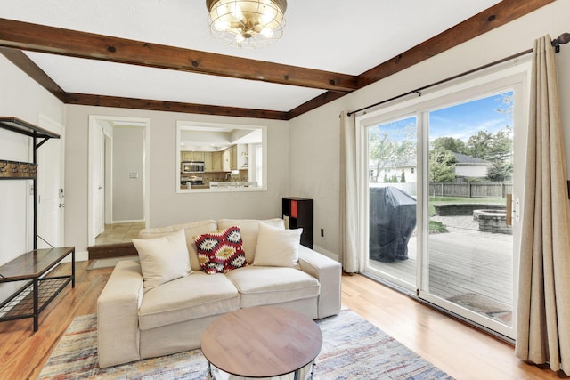 living room with light wood finished floors, beam ceiling, and baseboards