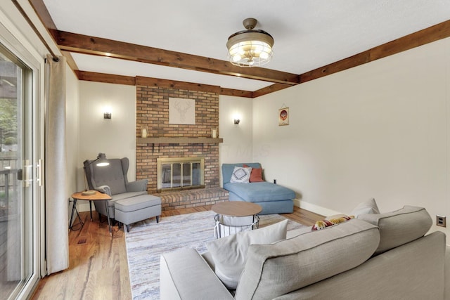 living room with beam ceiling, light wood-style flooring, a fireplace, and baseboards