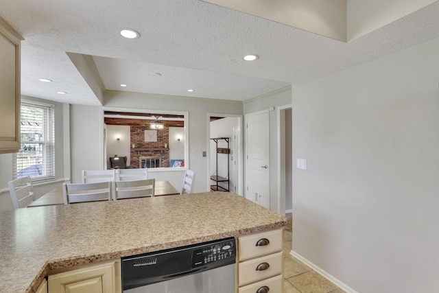 kitchen featuring dishwasher, a brick fireplace, light tile patterned floors, a textured ceiling, and baseboards