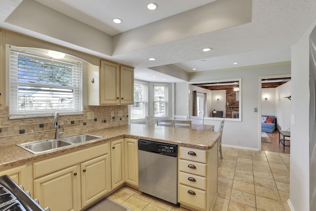kitchen featuring stainless steel dishwasher, a sink, a tray ceiling, a peninsula, and backsplash