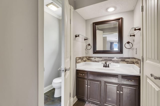 bathroom featuring toilet, vanity, backsplash, tile patterned flooring, and baseboards