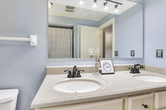 bathroom with toilet, double vanity, and curtained shower
