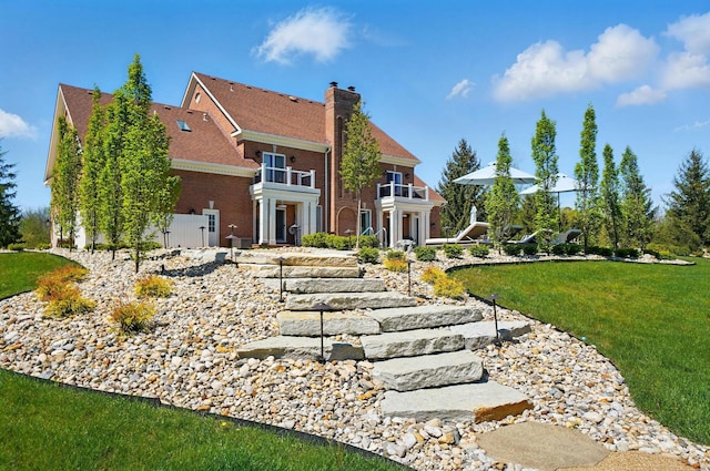8070 Harriott Rd, Dublin, OH 43017 - rear view of property featuring a balcony, a yard, brick siding, and a chimney