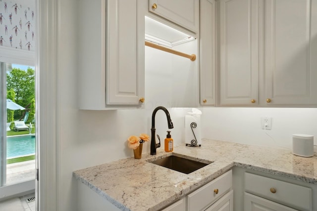 8070 Harriott Rd, Dublin, OH 43017 - kitchen featuring a sink, white cabinetry, and light stone countertops