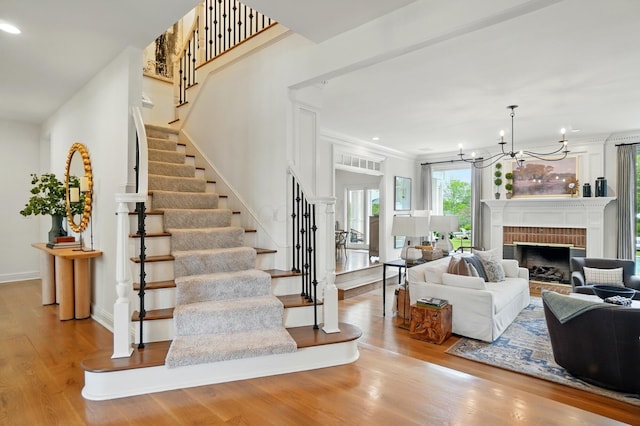 8070 Harriott Rd, Dublin, OH 43017 - living room with stairs, wood finished floors, a chandelier, recessed lighting, and a brick fireplace