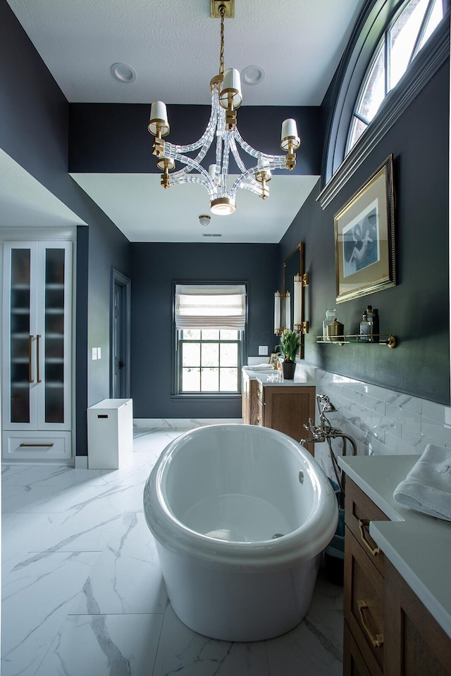8070 Harriott Rd, Dublin, OH 43017 - full bathroom with marble look tile flooring, a soaking tub, a chandelier, and vanity