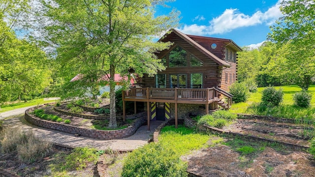 rear view of property featuring log exterior, a deck, and stone siding