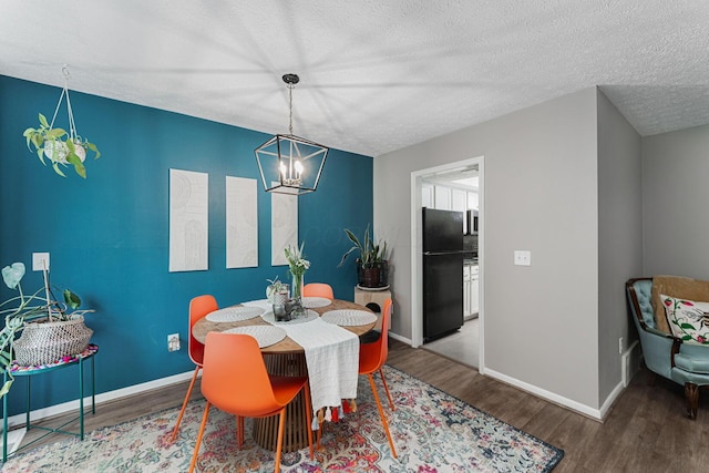 dining room featuring a chandelier, wood finished floors, a textured ceiling, and baseboards