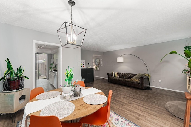 dining room with a textured ceiling, a chandelier, wood finished floors, and baseboards