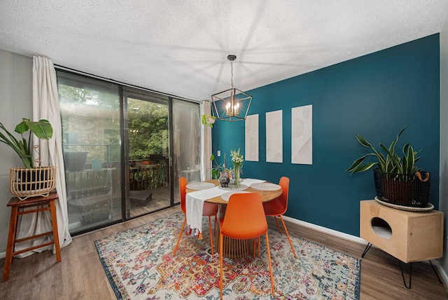 dining space featuring a textured ceiling, wood finished floors, a chandelier, and baseboards
