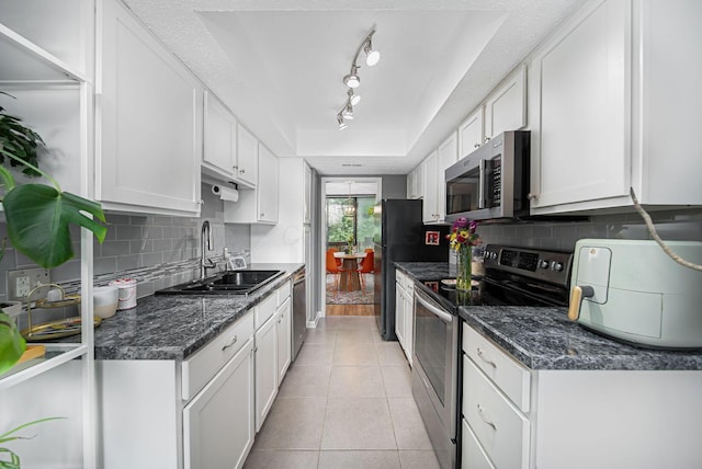 kitchen featuring stainless steel appliances, a sink, white cabinets, and tasteful backsplash
