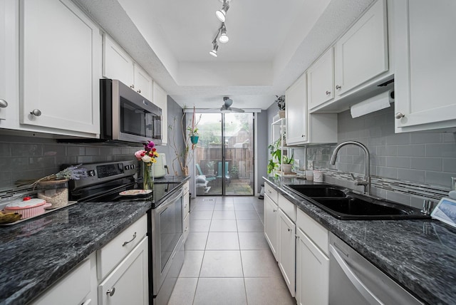 kitchen with appliances with stainless steel finishes, a sink, white cabinets, and a tray ceiling