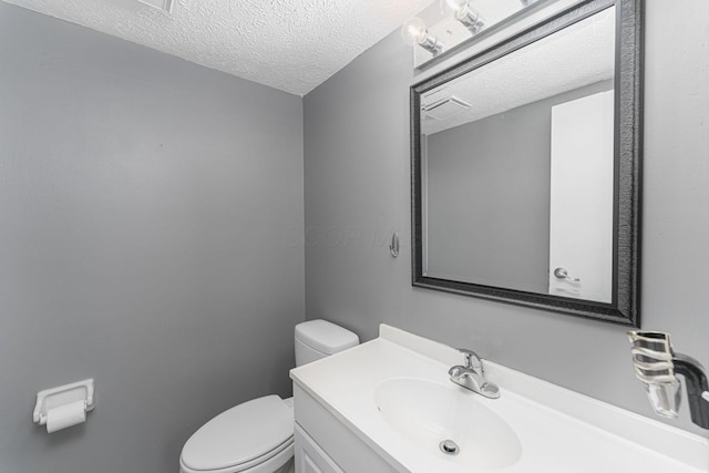 half bath with toilet, a textured ceiling, and vanity