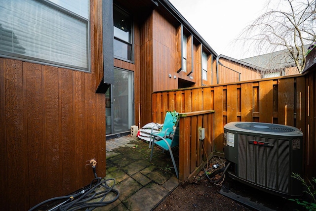 view of side of property with central AC unit, fence, and a patio