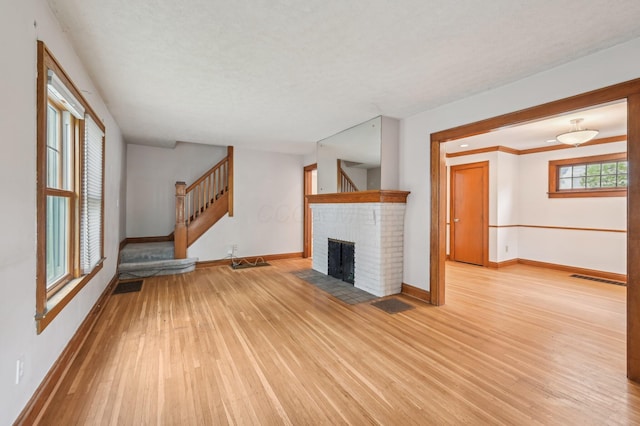 467 Brevoort Rd, Columbus, OH 43214 - unfurnished living room featuring baseboards, light wood finished floors, stairs, and a fireplace
