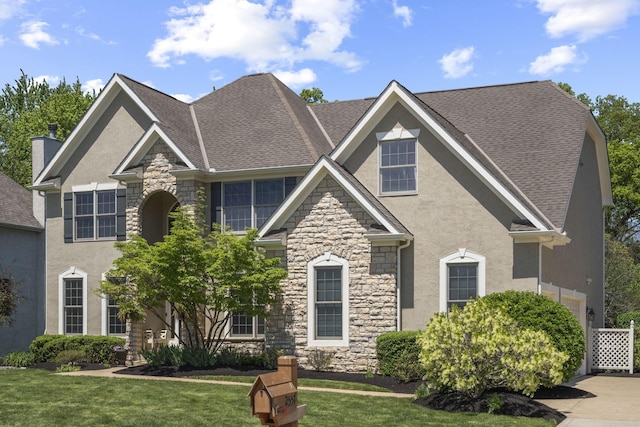 2557 Coltsbridge Dr, Lewis Center, OH 43035 - view of front of home with stone siding, stucco siding, a front lawn, and roof with shingles