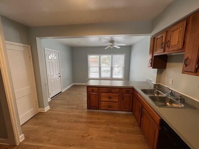 kitchen with a sink, dishwasher, brown cabinets, and a peninsula