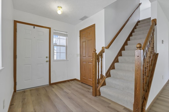 3625 Parker Knoll Ln, Columbus, OH 43219 - entryway with light wood-style flooring, stairs, a textured ceiling, and baseboards