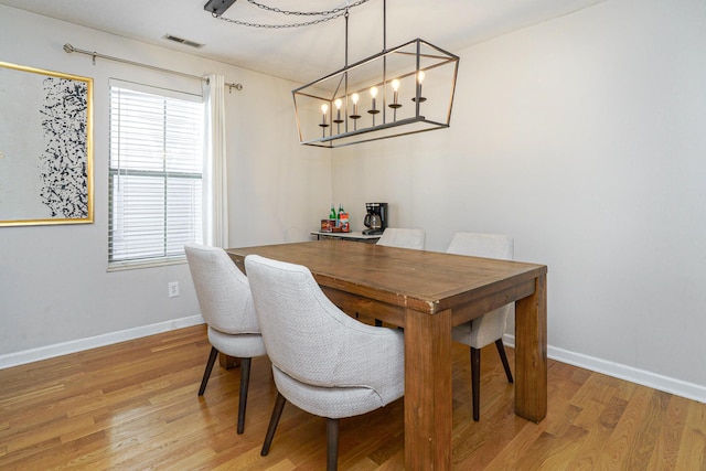 dining room featuring light wood-style flooring, a chandelier, and baseboards