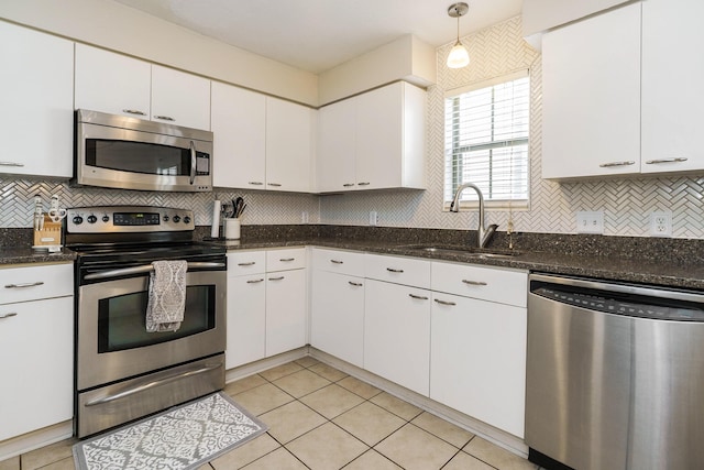 kitchen with stainless steel appliances, a sink, white cabinetry, and tasteful backsplash