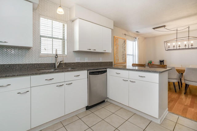 kitchen with stainless steel dishwasher, a sink, a peninsula, tasteful backsplash, and plenty of natural light