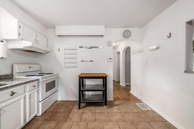 263 E Beaumont Rd, Columbus, OH 43214 - kitchen with white electric stove, under cabinet range hood, arched walkways, white cabinets, and baseboards