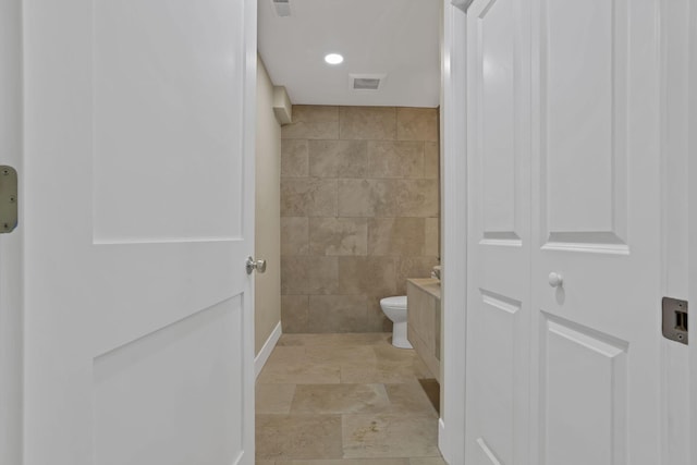 2727 Westmont Blvd, Columbus, OH 43221 - bathroom featuring tile walls, toilet, baseboards, stone finish flooring, and vanity