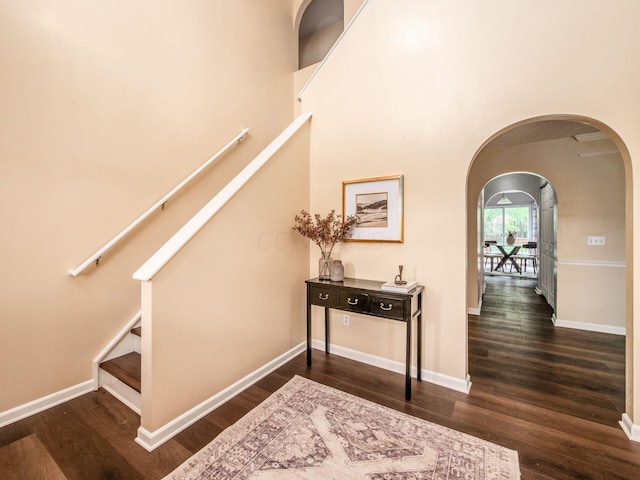 stairs featuring arched walkways, wood finished floors, and baseboards