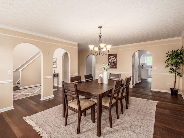 dining room featuring a textured ceiling, arched walkways, a chandelier, wood finished floors, and baseboards