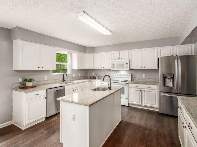 kitchen with appliances with stainless steel finishes, a sink, dark wood-style floors, a textured ceiling, and white cabinets