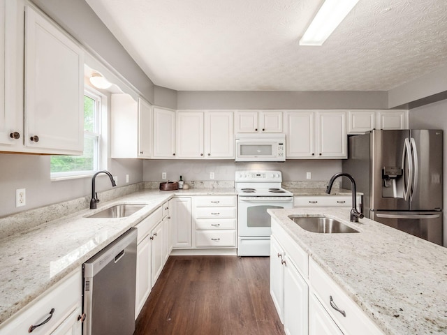 kitchen featuring stainless steel appliances, a sink, dark wood finished floors, white cabinets, and a textured ceiling