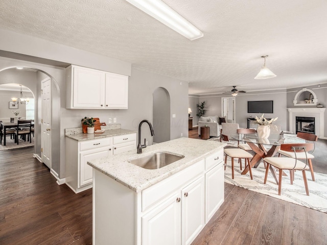 kitchen featuring a sink, arched walkways, open floor plan, and a textured ceiling