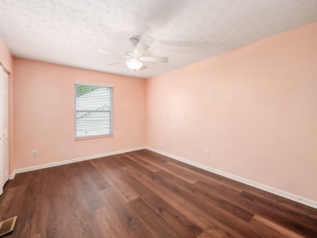 empty room with a ceiling fan, dark wood-style flooring, baseboards, and a textured ceiling