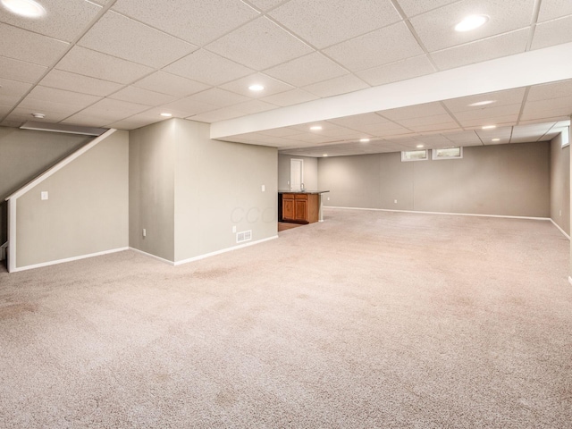 finished below grade area with baseboards, light carpet, a drop ceiling, recessed lighting, and bar area