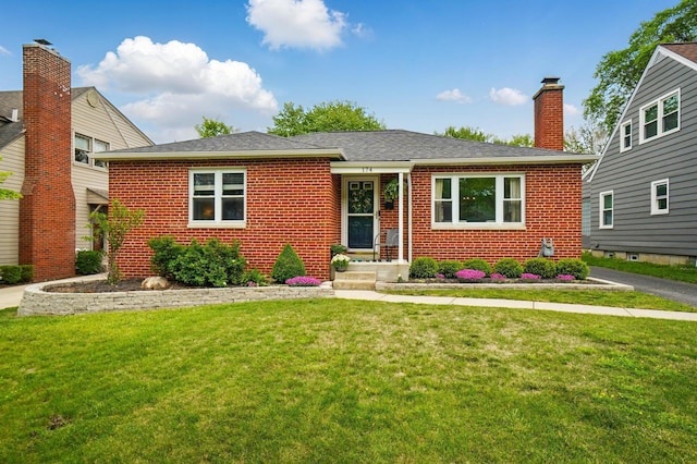 view of front of house featuring brick siding, a front lawn, and a chimney