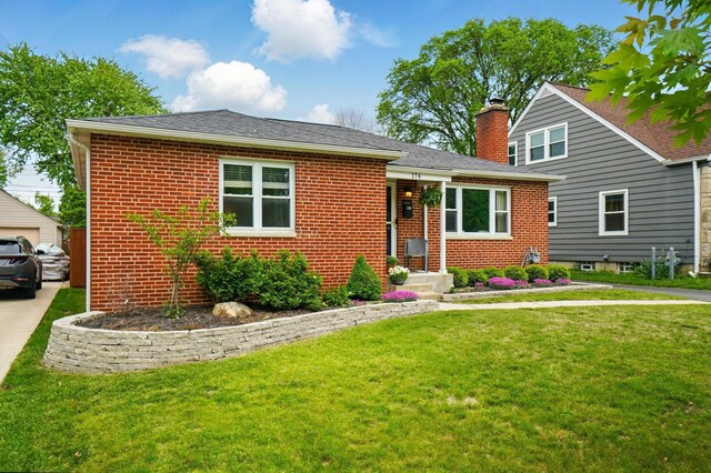bungalow with brick siding, a chimney, and a front yard