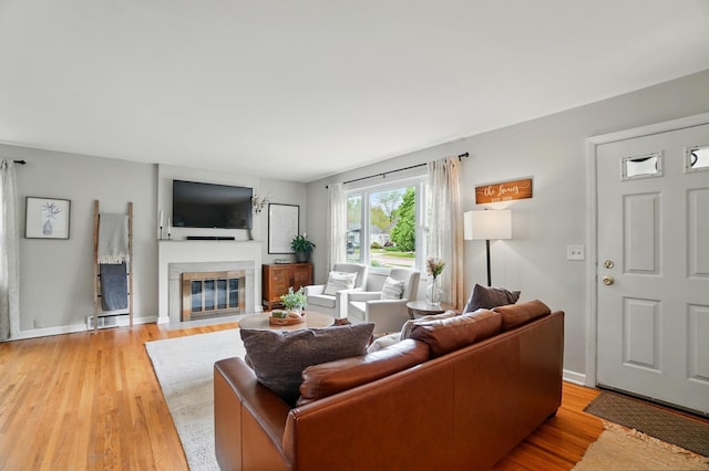 living room featuring a fireplace with flush hearth, light wood-type flooring, and baseboards