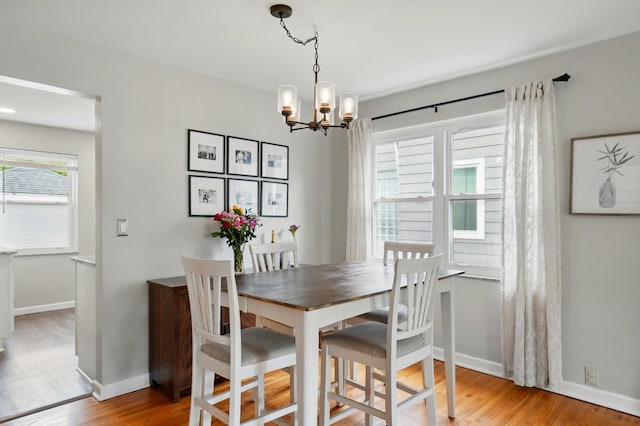 dining room with a chandelier, light wood-style flooring, and baseboards