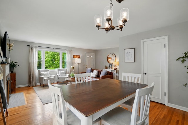 dining area with light wood-type flooring, a chandelier, and baseboards