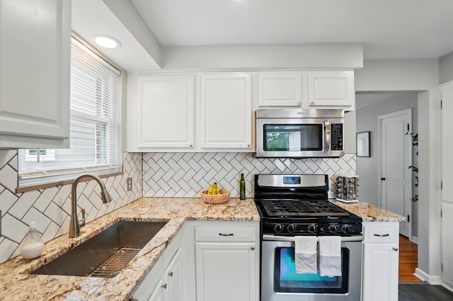 kitchen featuring appliances with stainless steel finishes, a sink, decorative backsplash, and white cabinets