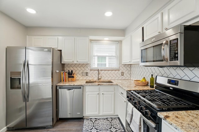 kitchen with appliances with stainless steel finishes, a sink, white cabinetry, decorative backsplash, and recessed lighting