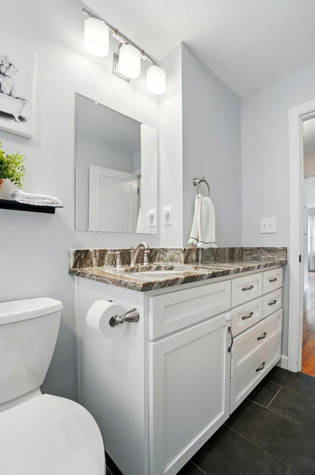 half bath featuring toilet, tile patterned flooring, and vanity
