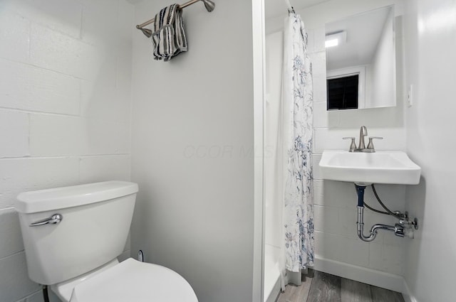 full bathroom featuring wood finished floors, toilet, a shower with curtain, a sink, and baseboards