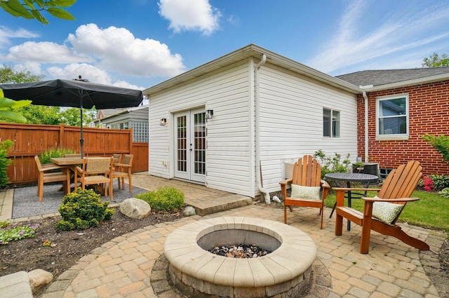 back of property featuring outdoor dining space, a patio, french doors, a fire pit, and fence
